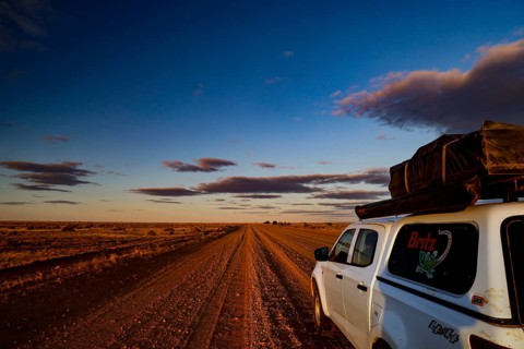 Vehicle on rural road under dramatic evening sky in outback, Oodnadatta Track, null, Australia