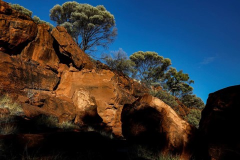 Massive rock formations with sparse vegetation and deep blue sky, Palm Valley, Northern Territory,