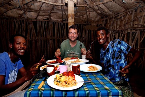 Three men enjoy a traditional dinner in a tent at camp in Ahmedela, Ahmedela, Ethiopia