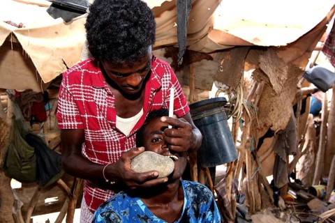 A man performs a dental ritual in the hut, Ahmedela, Tigray, Ethiopia