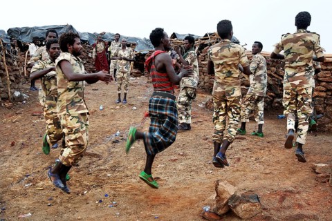 Soldiers dance in their military uniforms on rocky ground at Erta Ale Camp, Erta Ale, Ethiopia