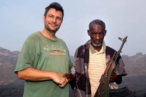 Police officer Muhammed stands next to a man in the volcanic landscape of Erta Ale, Erta Ale, Afar,