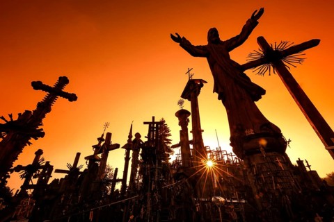 Crosses against light at sunrise on the Hill of Crosses in Siauliai, Siauliai, Lithuania
