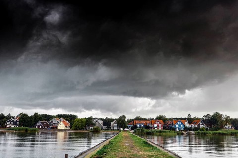Pier leads to a village under a dramatic sky in Pervalka, Pervalka, Lithuania
