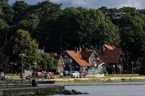 Picturesque red brick houses on the water surrounded by thick green forests, Juodkrante, Klaipeda,
