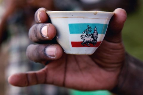 A hand holds a decorated cup during a coffee ceremony, Mayzebri, Ethiopia