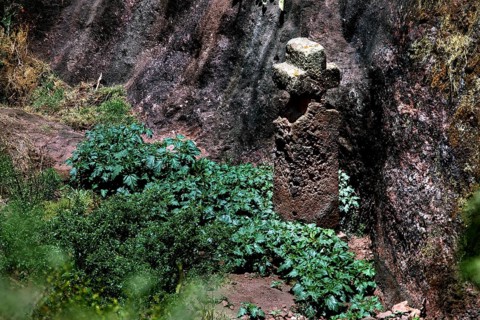 Cross in rocky surroundings surrounded by shrubs, symbolic representation in Lalibela, Lalibela,