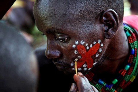 A hamer receives elaborate red and white face painting as part of an initiation ritual, Turmi,
