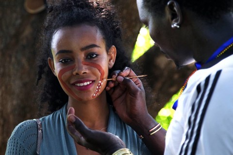 Tourist receives face painting from a hammer during an initiation ritual, outdoor cultural