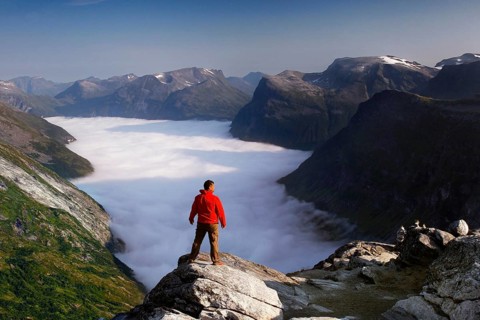 View from Dalsnibba of the Geiranger Fjord with a sea of clouds, enjoyed by a hiker