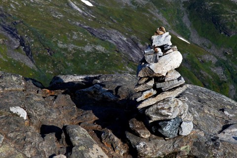 Stone pyramid on rocky outcrop with green hills in the background, Geirangerfjord, Dalsnibba,