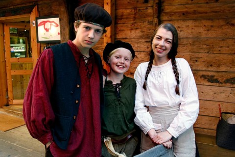 Group of people wearing traditional clothes in a historic wooden house alley, Bergen, Norway