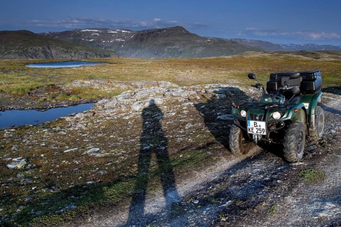 ATV is standing on a dirt road next to a long shadow of people in the vast countryside, zero