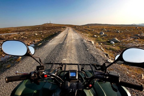 View from an ATV of a long dirt road in vast landscapes under clear skies, zero