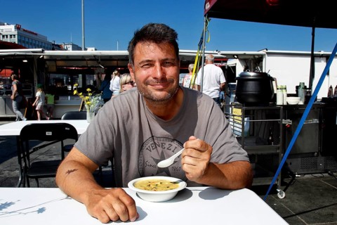 Smiling man eating at fish market in sunshine, Bergen, Hordaland, Norway