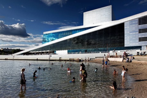 Modern opera next to beach, people enjoying sunny day in water, Oslo, Norway
