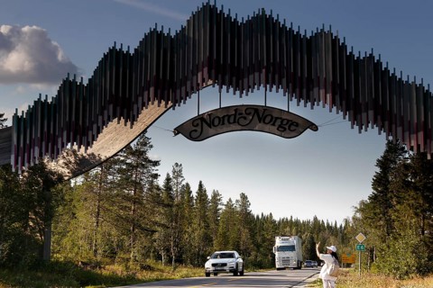 Distinctive wooden archway across the road with passing cars, zero