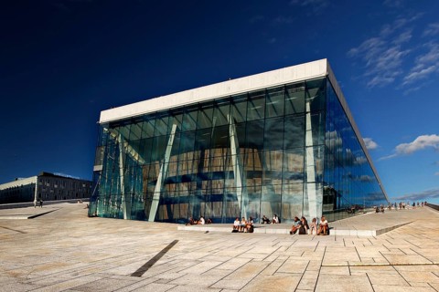 Glass façade of Oslo Opera, an architectural masterpiece in the Bjøvika district under clear skies,