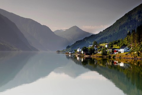 Tranquil fjord landscape with mountains and a small village reflected in the water, Mundal, Norway