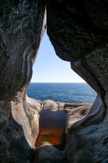 View from a rocky cave over the blue sea in bright sunshine. Summer, Brufjellhålene (Antrum),