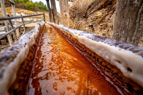 Brine rich in iron and minerals flows through a wooden channel at the ancient salt flats of anana