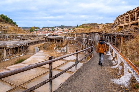Woman walking along a path next to the historic terraced salt evaporation ponds of the salt valley,