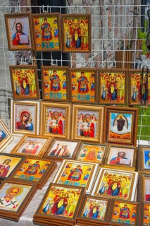 Icons in various frames with bright colors depict religious figures at a market stand, stand in