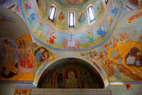 Interior of a church painted with colorful frescoes and biblical scenes in the dome, domed church