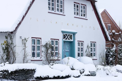 Decorative old thatched roof house covered with snow flurries in winter, Schleswig-Holstein,