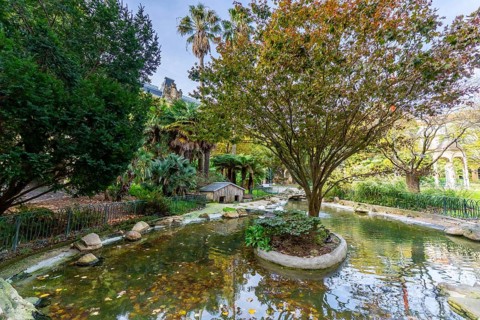 Gipuzkoa square showcasing a tranquil pond and green trees with hints of autumn foliage, reflecting