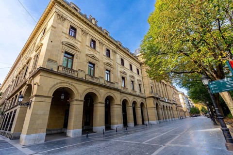 Gipuzkoa square facade in san sebastian with repeating stone arches and windows along a tree lined