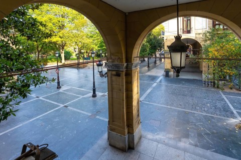 Arched arcade entrance providing a view through to gipuzkoa square park in san sebastian, featuring