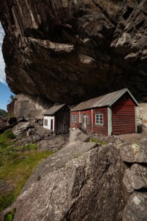 Historical wooden houses sheltered under a massive rock overhang. Summer, Helleren (Helleren),