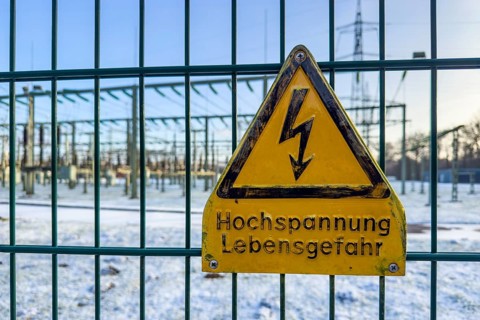 Recording of snow in winter warning sign warning high voltage danger to life on fence from behind