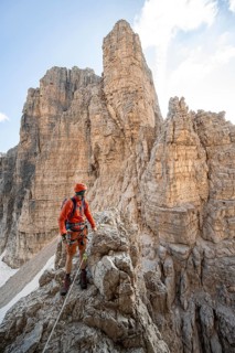 Mountaineer climbs on an exposed rock in the secured Via Ferrata Bocciere Centrale via ferrata,