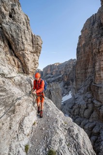 Mountaineer climbs an exposed rock band in the secured via ferrata Bocciere Centrale, Brenta