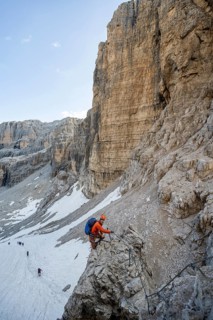 Mountaineer climbs on an exposed rock in the secured Via Ferrata Bocciere Centrale via ferrata,