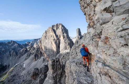 Mountaineer climbs an exposed rock band in the secured Via Ferrata Bocciere Centrale via ferrata,