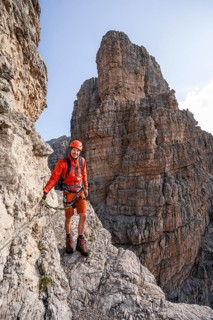 Mountaineer climbs an exposed rock band in the secured Via Ferrata Bocciere Centrale via ferrata,