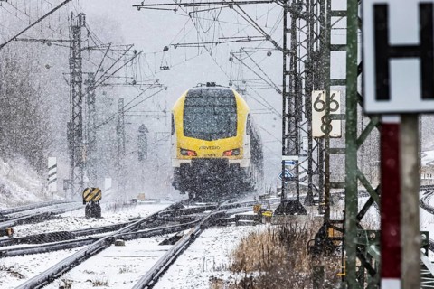 Regional train from Arverio on its way through a winter landscape in snowfall. The railcar train is