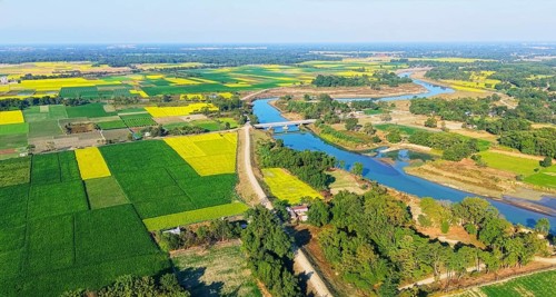 An aerial view reveals a gently curving river winding through the countryside, its silvery surface