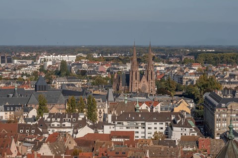 The stone balcony offers a view of the city of Strasbourg. Houses and buildings can be seen under a