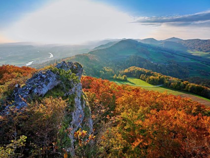 View of an autumnal forest from the Gisliflue, behind the Jura foothills with Wasserfluh and