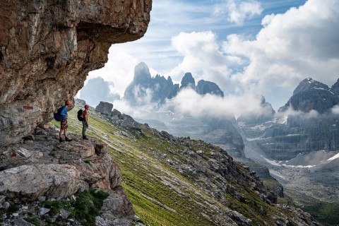 Two mountaineers on a path in front of a picturesque mountain landscape with rocky peaks, Via