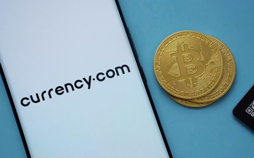 Dhaka, Bangladesh- 22 June 2025: Currency.com logo on smartphone screen near Bitcoin coin and QR