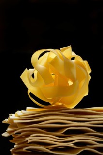 Uncooked lasagna leaves and fettuccine, noodle nest