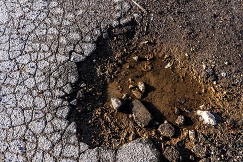 Pothole, asphalt surface, floor, with many small cracks, roadway, parking lot