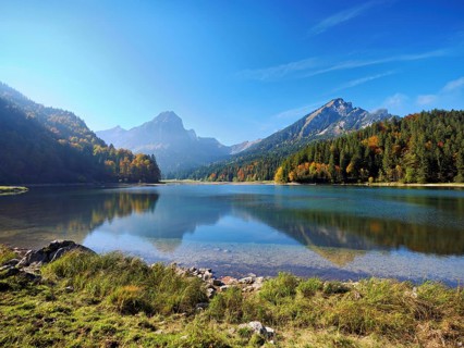 Autumn-colored forest is reflected in Obersee, Näfels, Canton of Glarus, Switzerland
