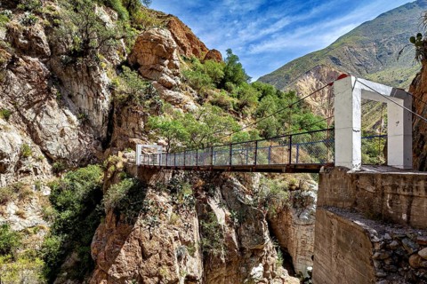 Suspension bridge between rocks under a blue sky, The landscape of the Colca Canyon in the Andes of