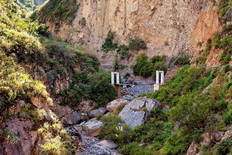 Small bridge over a rocky gorge surrounded by lush vegetation, The landscape of Colca Canyon in the